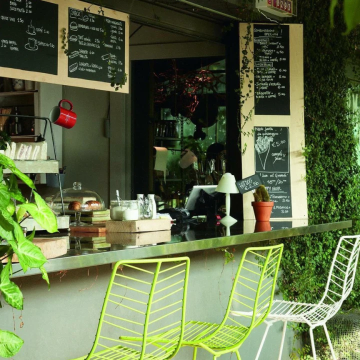 En bar i skarpe grønntoner med mye planter, grønne barstoler og organisk interiør.
